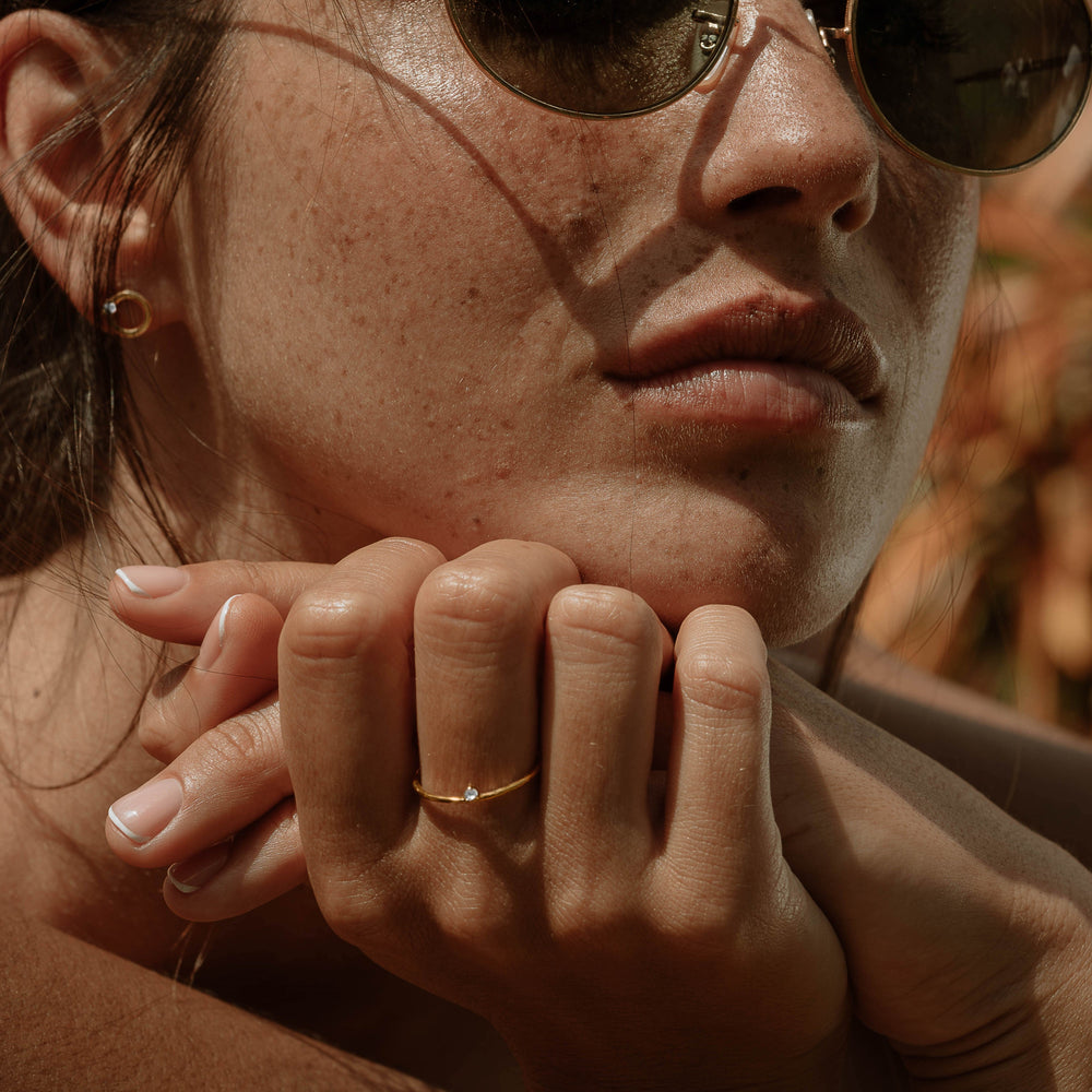 A woman wearing sunglasses, ScÃ©ona minimalist gold ring Ili, and ScÃ©ona gold studs earrings Jumna
